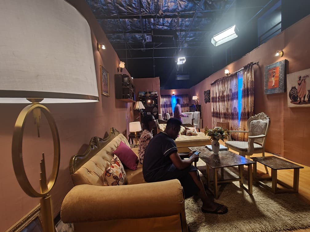 A lounge set with gold sofas and patterned curtains on the ContentGram Studios Africa sound stage, studio lights overhead