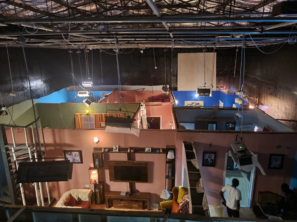 The ContentGram Studios Africa sound stage from above — a pink living-room set and blue rooms beside it, with lights rigged over every set