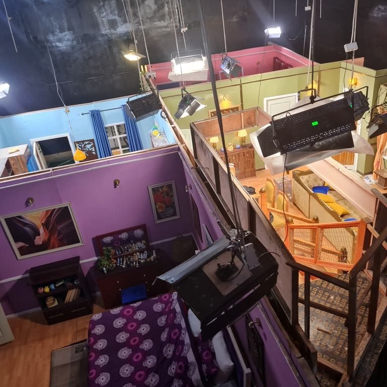 The multi-room set seen from the lighting grid, lamps rigged overhead
